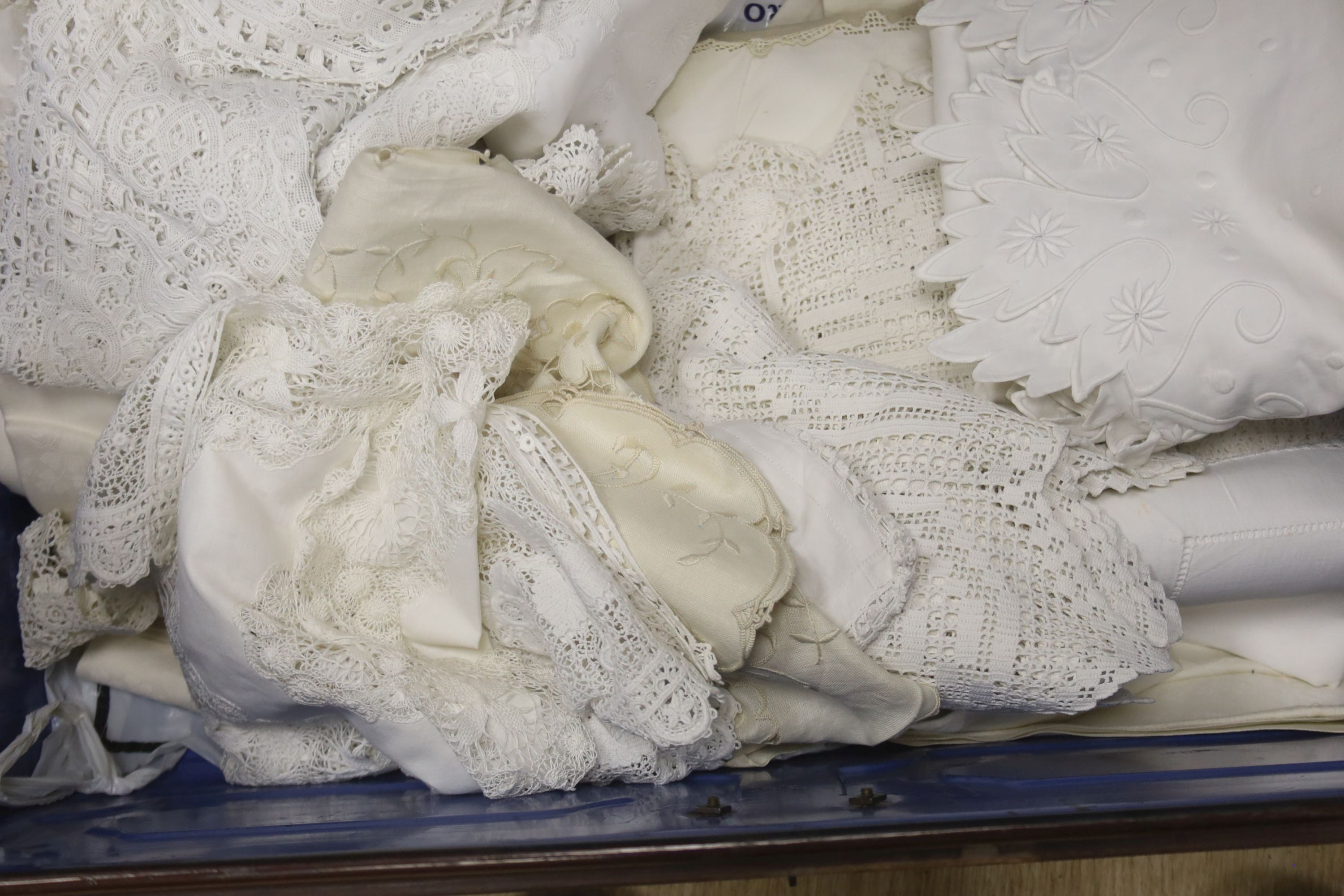 A tin trunk containing a scalloped linen sheet with embroidered monogram linen crochet tablecloths, chemical lace cloth etc.